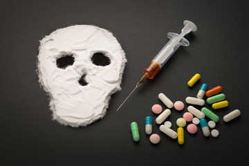 Narcotic powder in the form of a skull and syringes with injection. The concept of addiction kills.