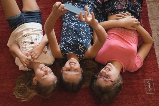 Overhead view of siblings using smartphone at home