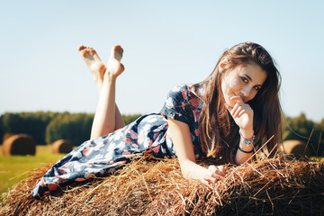 Teenager girl in an autumn field with hay stack - obrazy, fototapety, plakaty