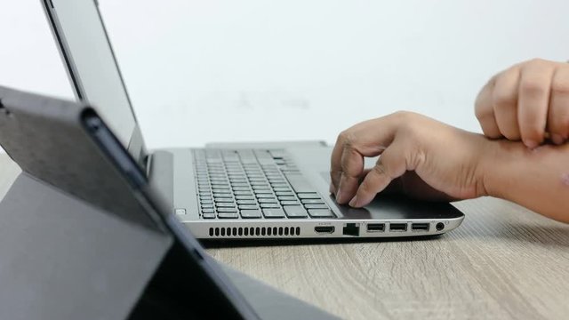 Hands of man using laptop computer and scratching to arm skin rash psoriasis