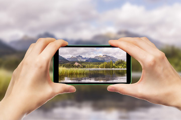 Dłonie trzymające telefon komórkowy. Fotografowanie górskich krajobrazów za pomocą smartphone.  © art08