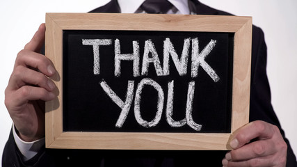 Thank you written on blackboard in businessman hands, donation appreciation