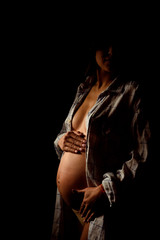 Belly of pregnant woman over dark background, nine month.Pregnant girl