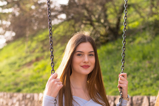Young girl portrait sitting on swing in park