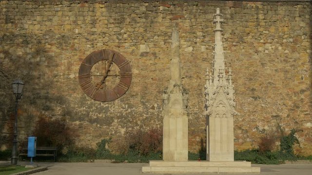 A clock on a stonewall and two church towers