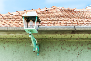Green street lamp or lantern on the exterior wall facade of house to provide light at the night
