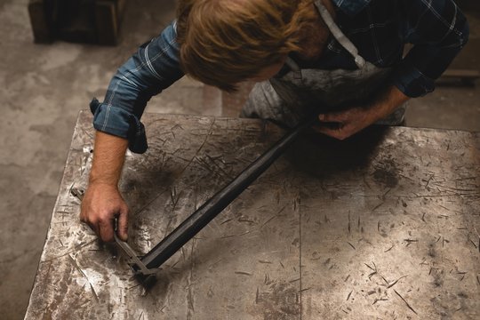 Blacksmith measuring a metal rod with caliper