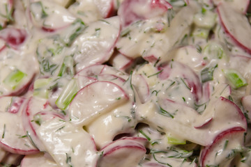 Spring salad with radish, dill and green onions and sour cream close-up