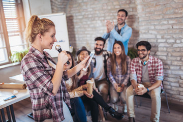 Business people making team training exercise during team building seminar singing karaoke.