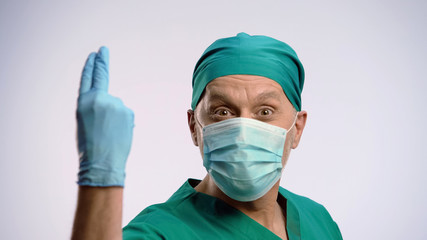 Fototapeta na wymiar Funny man wearing scrubs and face mask pretending to be proctologist, crazy joke
