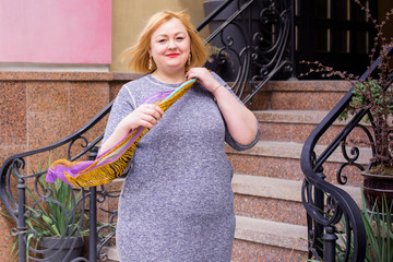 A woman of plus size, American or European appearance walks at city streets enjoying life. A young lady with excess weight, have a stylish dress. Natural beauty 