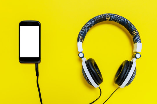 Smartphone and headphone with jeans jacket on a yellow background, isolated