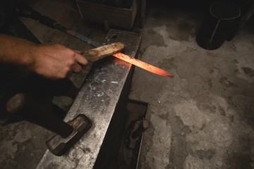 Blacksmith examining a hot metal rod