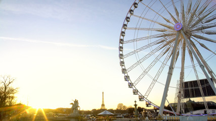 Sunset in Paris, Eiffel Tower on cityscape horizon, observation wheel rotating