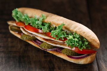 Grilled chicken sandwich on wooden table.