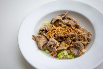 Fried pork with crunchy garlic, pepper and vegetable on white ceramic dish
