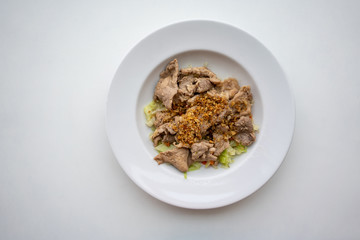 Fried pork with crunchy garlic, pepper and vegetable on white ceramic dish