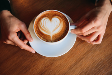 Overhead view of a Woman sitting at a table about to drink a cappuccino