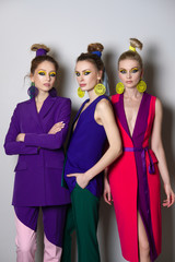 Three gorgeous fashion models with colorful make up and in bright designers clothes