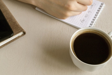 Top view of the goals list for the day, a Cup of coffee on a bright table.