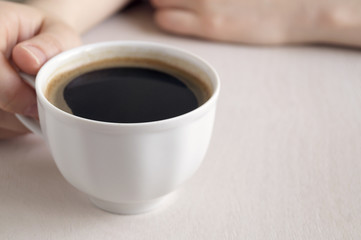 Hands holding a Cup of coffee on a bright table.