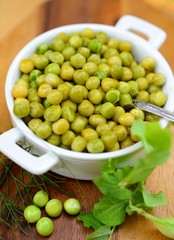 Boiled young green peas in a white bowl.