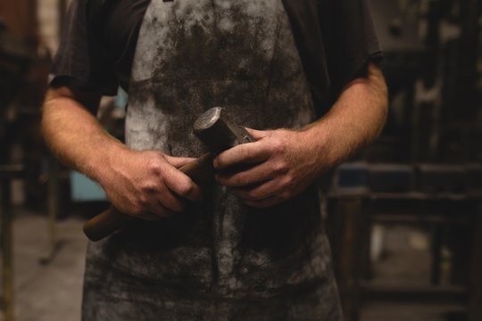 Blacksmith holding a hammer in workshop