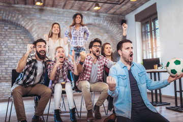 Happy friends or football fans watching soccer on tv and celebrating victory. Friendship, sports and entertainment concept.