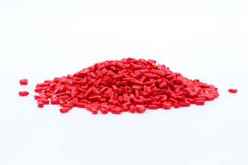 Red plastic polymer granules on white background.