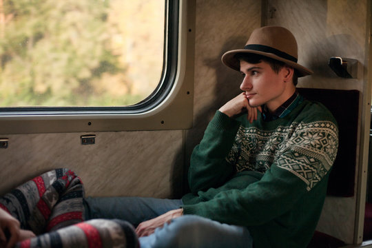Thoughtful man traveling in train and looking out through window