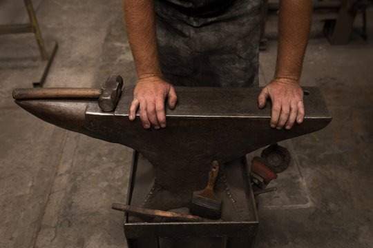 Midsection of blacksmith working in workshop
