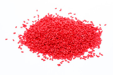 Red plastic polymer granules on white background.