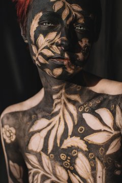 Portrait of a woman in black and gold body paint