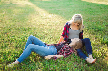 Fototapeta premium Two happy female friends playing and having fun in green grass