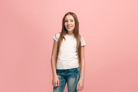 The happy teen girl standing and smiling against pink background.