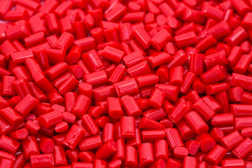 Red plastic polymer granules on white background.