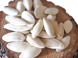 white pumpkin seeds on white wood slice with isolated white background