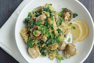 Yellow rice with mushrooms and spinach. Vegan dish. European cuisine. Vegetarian turmeric rice in the white bowl. Meatless. Top view.