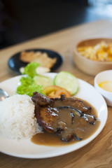 Close-up shot of a plate of pork chops with mushroom sauce over some warm white rice