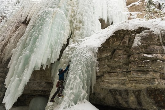 Rock climber climbing rocky mountain during winter
