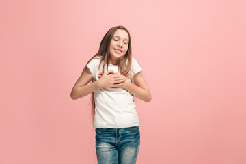 The happy teen girl with phone standing and smiling against pink background.