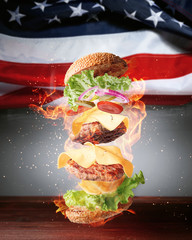 a fiery flying burger against the background of the American flag. picnic concept in honor of...