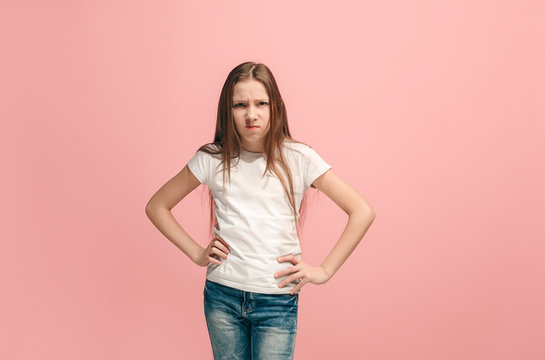 Portrait of angry teen girl on a pink studio background