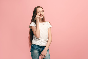 The happy teen girl standing and smiling against pink background.