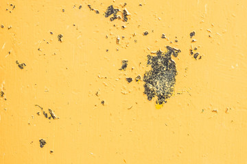 Close-up view a weathered damaged metal wall with yellow peeling paint and cracked stucco layer. Pattern of rustic blue grunge material from old wall seamless texture.
