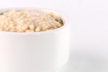 breakfast: oatmeal porridge in white bowl on white background. Isolated