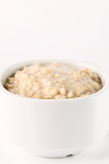 breakfast: oatmeal porridge in white bowl on white background. Isolated