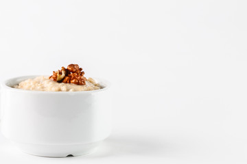 breakfast: oatmeal porridge with wallnuts in white bowl on white background. Isolated