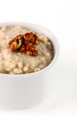 breakfast: oatmeal porridge with wallnuts in white bowl on white background. Isolated