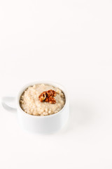 Obraz na płótnie Canvas breakfast: oatmeal porridge with wallnuts in white bowl on white background. Isolated
